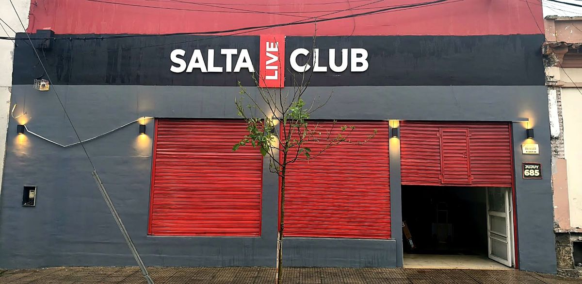 Fachada de día: frente gris con cartel Salta LIVE Club y tres persianas rojas